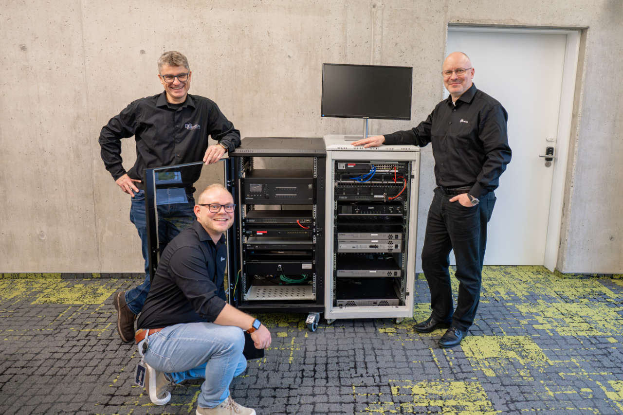 Das Fachplanungsteam von EXG MEDIA GmbH vor einem Hardware-Rack mit Eventtechnik
